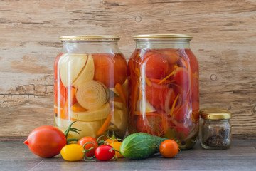 Preserving fresh vegetables red tomatoes in two glass jars on wooden background surface