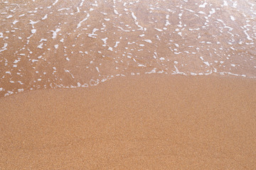 Sand beach. A sea wave on yellow sand. Abstract marine background.