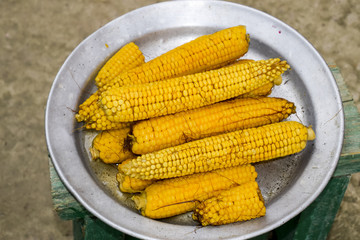 Boiled corn on an aluminum tray. Yellow boiled young corn, useful and tasty food