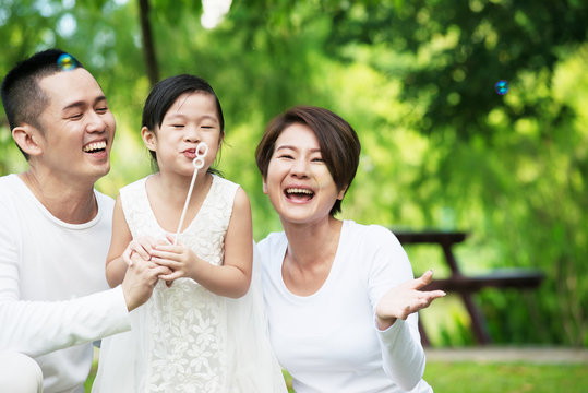 Young Happy Asian Family Spending Time Together At The Park.