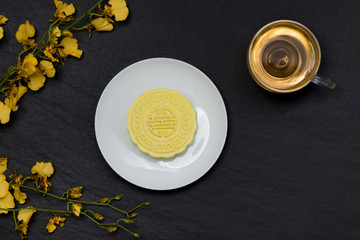 Sweet color of snow skin mooncake and tea cup with flowers on dark background.