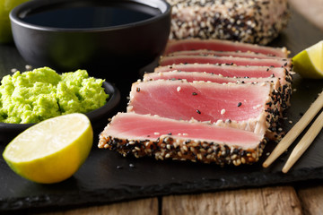 Tuna fillet in sesame and soy sauce, wasabi, lime closeup on a table in Asian style. horizontal