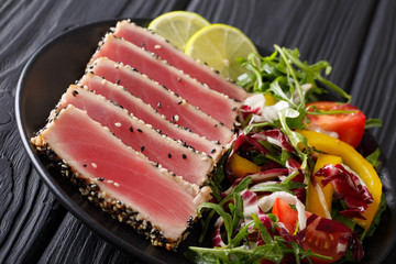 Delicious Tuna Steak in sesame, lime and salad of fresh vegetables and herbs close-up. horizontal