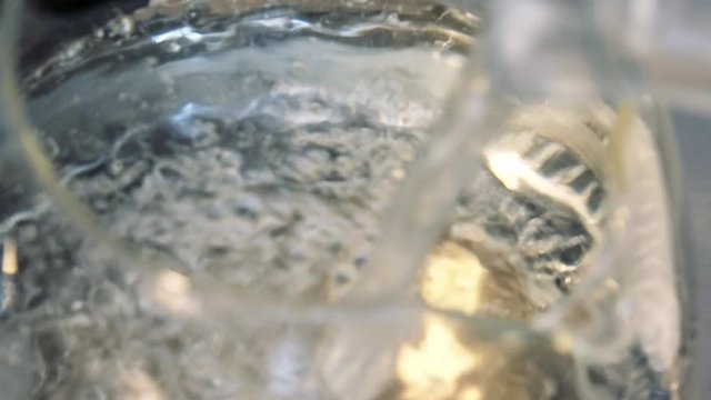 Water is poured into a glass kettle - closeup from above