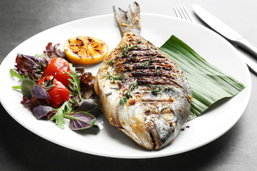 Plate with delicious fried fish on table