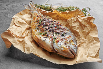 Paper with delicious fried fish on table