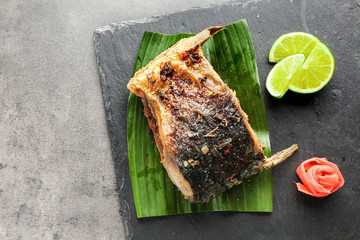 Slate plate with delicious fried fish on table