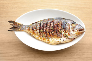 Plate with delicious fried fish on wooden table