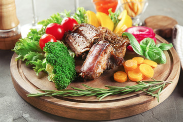 Delicious roasted ribs and vegetables on wooden board