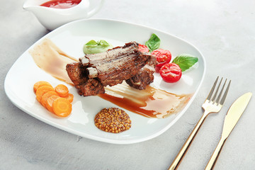 Plate with delicious ribs on table
