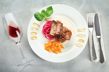 Plate with delicious ribs on table