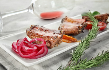 Plate with delicious ribs and glass of wine on table