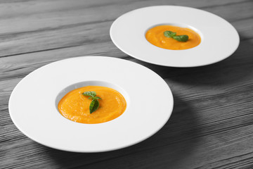Plates with delicious carrot soup on wooden table