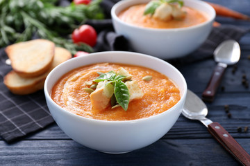 Bowl with delicious carrot soup on wooden table