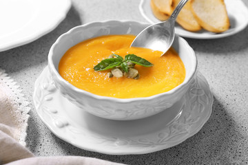 Bowl and spoon with delicious carrot soup on table