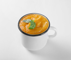 Mug with delicious carrot soup on white background