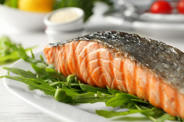 Plate with slice of delicious grilled salmon on table