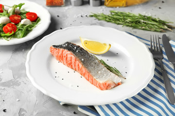 Plate with slice of delicious salmon on table