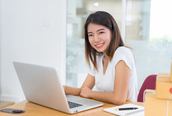 Young asian girl freelancer business private working at home office with laptop, note, coffee, packaging delivery online market on purchase orders to customer.