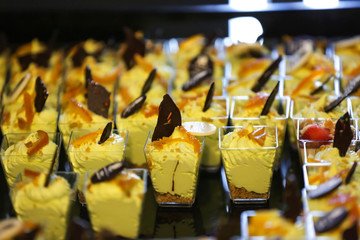 Many glasses with yellow mini desserts closeup