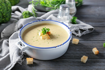 Broccoli cheddar soup in casserole on wooden kitchen table