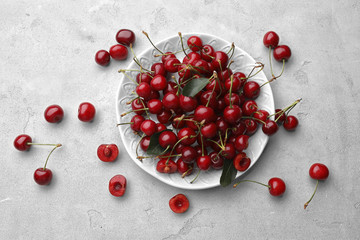 Plate with fresh ripe cherries on table