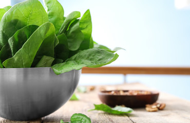 Bowl with fresh spinach leaves on table