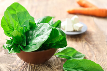 Bowl with fresh spinach leaves on table