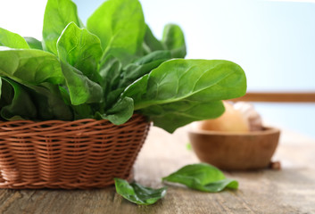 Obraz premium Wicker basket with fresh spinach leaves on table