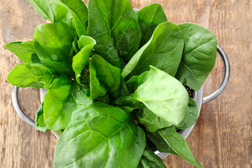 Colander with fresh spinach leaves on table