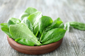 Bowl with fresh spinach leaves on table