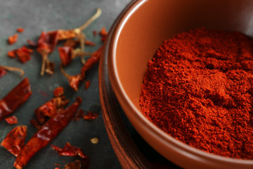 Red chili powder and dried pepper pods on table, closeup