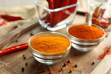 Chili powder in glass bowls on wooden cutting board