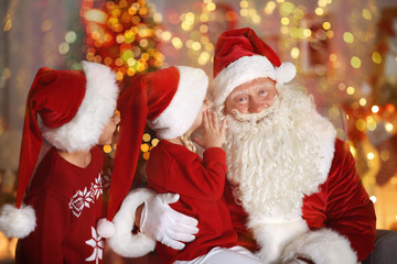 Cute little boy and girl with Santa Claus in room decorated for Christmas