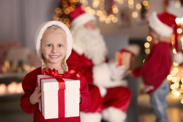 Fototapeta na wymiar Cute girl holding gift box in room with beautiful Christmas decorations