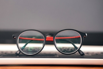 Fototapeta na wymiar Vintage style glasses resting on a black laptop.