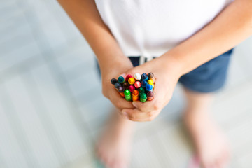 child's hands with lots of colorful wax crayons