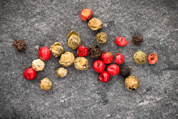 Peppercorns over black stone background. Top view.