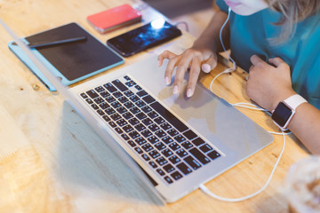 Close up Asian woman wearing pink smartwatch and working with her laptop in coffee shop in selective focus.