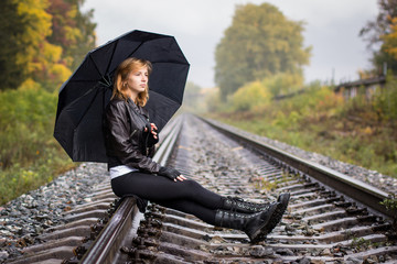 Girl, umbrella and rails in autumn