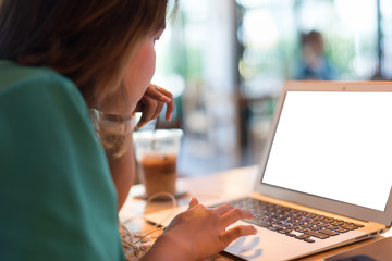 Close up Asian woman wearing pink smartwatch and working with her laptop in coffee shop in selective focus.