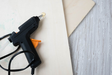 Electric hot glue gun on wood background. the concept of repair or creativity background