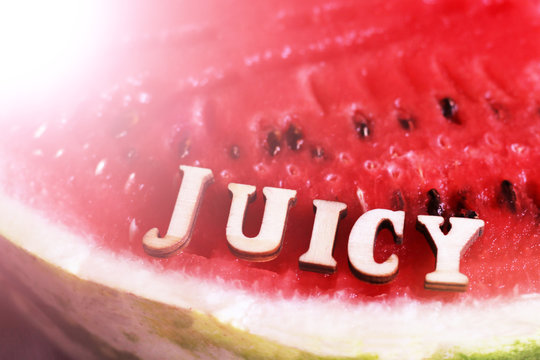 Red juicy watermelon in the sunlight, wooden letters

