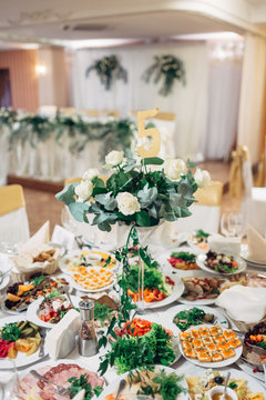 Rich served dinner table decorated with white roses and green branches