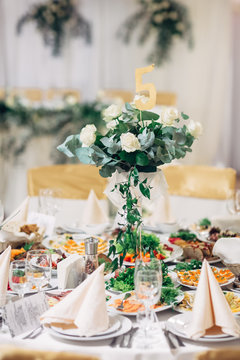 Tall vase with bouquet of white roses stands on dinner table