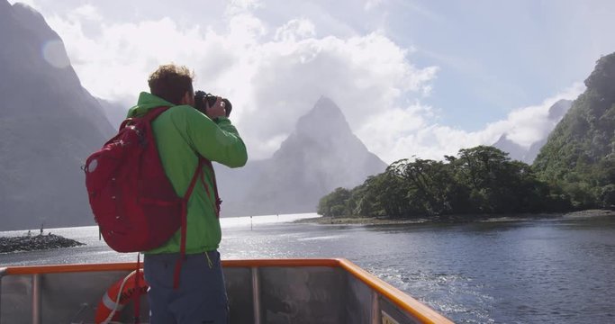 Landscape travel photographer tourist taking photo of Milford Sound and Mitre Peak in Fiordland National Park, New Zealand while on cruise ship boat tour.