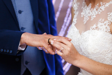 bride wearing the golden ring on finger of her husband