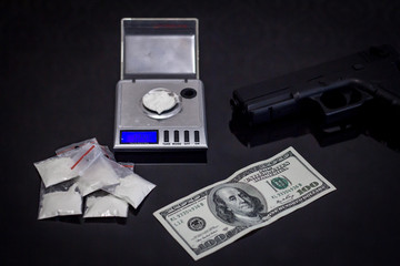 scales with cocaine, many dollars and hand gun on black background