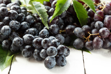 Ripe dark grapes with leaves, on white background. Selectiva focus.