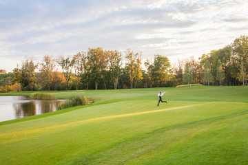 Young adult girl runs on the green grass of the golf course. The girl happiness.